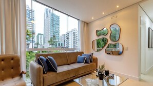 A modern living room with a sofa, a glass coffee table, and decorative mirrors on the wall.
