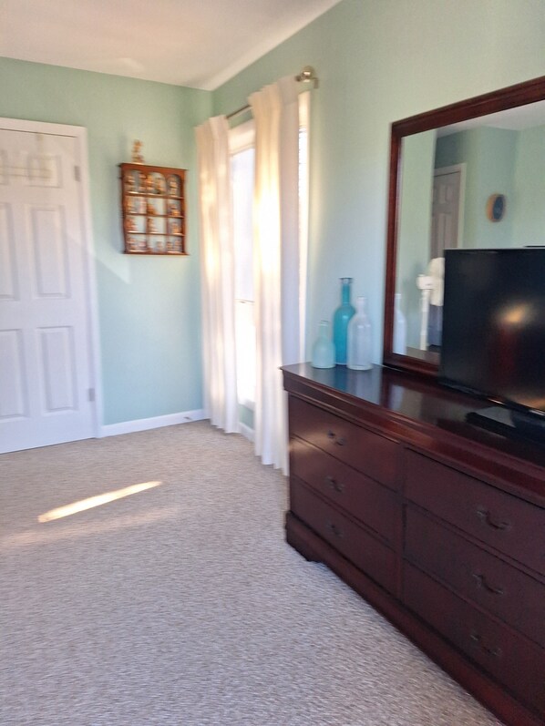A room with a wooden dresser, a television, and a door. - Charming 2-BD Townhome, POOL, SLEEPS 6 - short walk to town, beach & boardwalk (Rehoboth Beach)