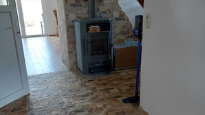 A room with a stone fireplace, a wooden ceiling beam, and a tiled floor. - Vacation home "Ohana" Cozy vacation home for the whole family, close to the water (Torgelow)
