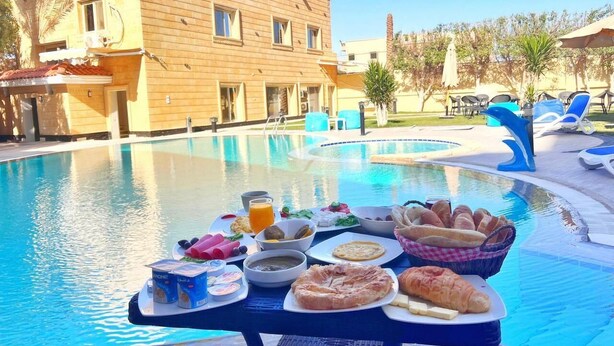 A poolside breakfast setup with various food items and a pool in the background.