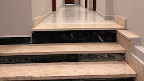 A hallway with marble steps leading to a door at the end.