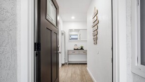 A hallway with a dark wooden door, white walls, a white cabinet, and a small window. - Modern Mountain View home (Lompoc)