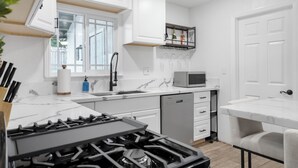 A modern kitchen with white cabinetry, a built-in microwave, and a gas stove. - Modern Mountain View home (Lompoc)