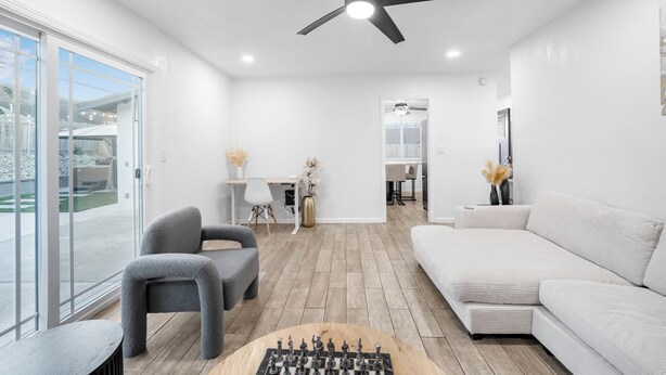 A modern living room with a sofa, chairs, a coffee table with a chess set, and a ceiling fan. - Modern Mountain View home (Lompoc)