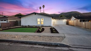 A single-story house with a garage, a well-maintained lawn, and a driveway leading to the garage. - Modern Mountain View home (Lompoc)