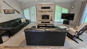 A living room with a fireplace, a black leather sofa, a wooden coffee table, and a television. - Lakeside Serenity Meets Northern Adventure, Stunning Sunsets, Family Getaway! (Nevis)