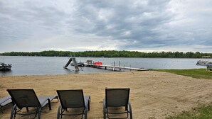 A beach with three lounge chairs, a dock, and a boat. - Lakeside Serenity Meets Northern Adventure, Stunning Sunsets, Family Getaway! (Nevis)