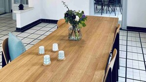 Ein Essbereich mit einem Holztisch, Stühlen, einer Blumenvase und einer Pendelleuchte.