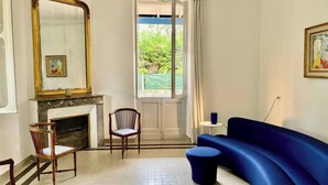 Ein Zimmer mit Kamin, einem blauen Sofa, einem Holzstuhl und einem großen Spiegel.