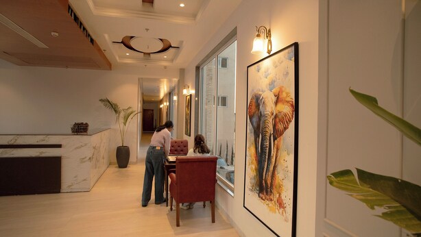 Un moderno vestíbulo de hotel con una recepción, un área de comedor con dos sillas y un cuadro grande en la pared.