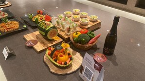 Una mesa de buffet con diversos platos, una botella de vino y un código QR para comentarios.