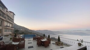 Una terraza con asientos al aire libre y vistas a las montañas.