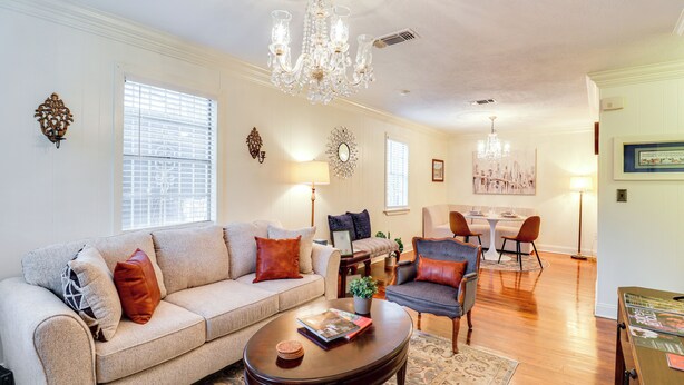 A living room with a sofa, armchair, coffee table, chandelier, and dining area. - 3 Mi to Mississippi Stadium: Cozy Jackson Getaway! (Jackson)