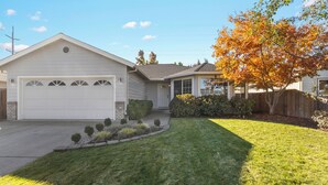 Ein Wohnhaus mit Garage, gepflegtem Rasen und einem Baum mit Herbstlaub.