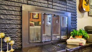 A modern interior with a stone wall, a glass door leading to a room, a guitar on the wall, and a plant on the counter.