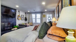 A bedroom with a bed, a TV, a fireplace, and a window.