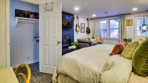 A bedroom with a bed, a TV, guitars, and a window.