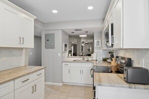 A modern kitchen with white cabinetry, a marble countertop, and a built-in oven.