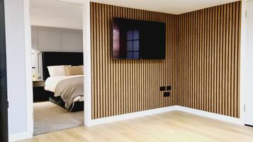 Un dormitorio con cama, televisor montado en la pared y diseño de pared con listones de madera.