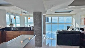 Ein modernes Interieur mit Kücheninsel, Wohnbereich und Meerblick sowie einem großen Fenster.