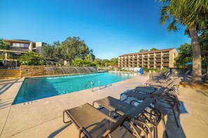 A swimming pool with lounge chairs and a waterfall feature.