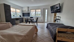 Una habitación con dos camas, kitchenette, comedor y televisor.