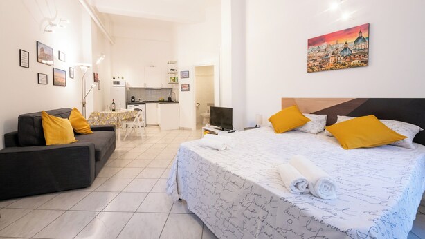 A hotel room with a bed, a sofa, a dining table, and a kitchen area. - La Dolce Vita Apartment - metro Jonio (Roma)