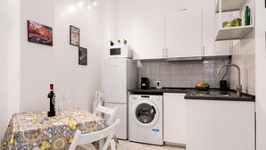 A compact kitchen with a washing machine, a coffee maker, and a sink. - La Dolce Vita Apartment - metro Jonio (Roma)