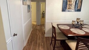 Un coin repas avec une table en bois, des chaises et un tableau accroché au mur.