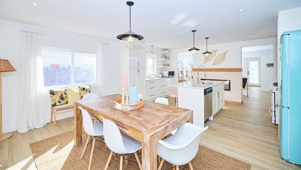 Una cocina moderna con armarios blancos, una mesa de comedor de madera y un refrigerador azul.
