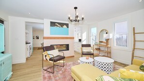 Una sala de estar moderna con chimenea, un comedor y una cocina a la vista.