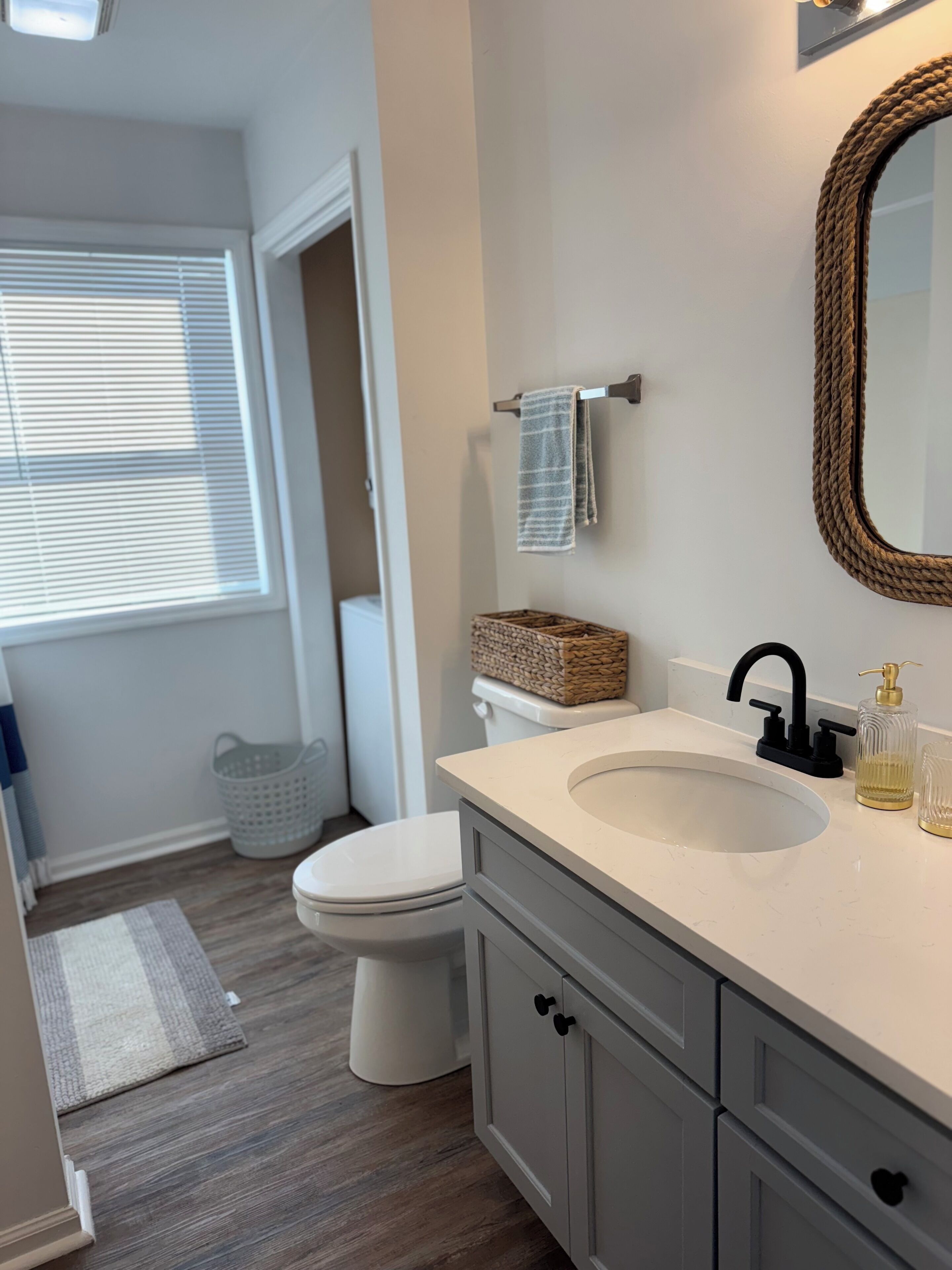 A bathroom with a white sink, a mirror, a toilet, and a basket on the wall.