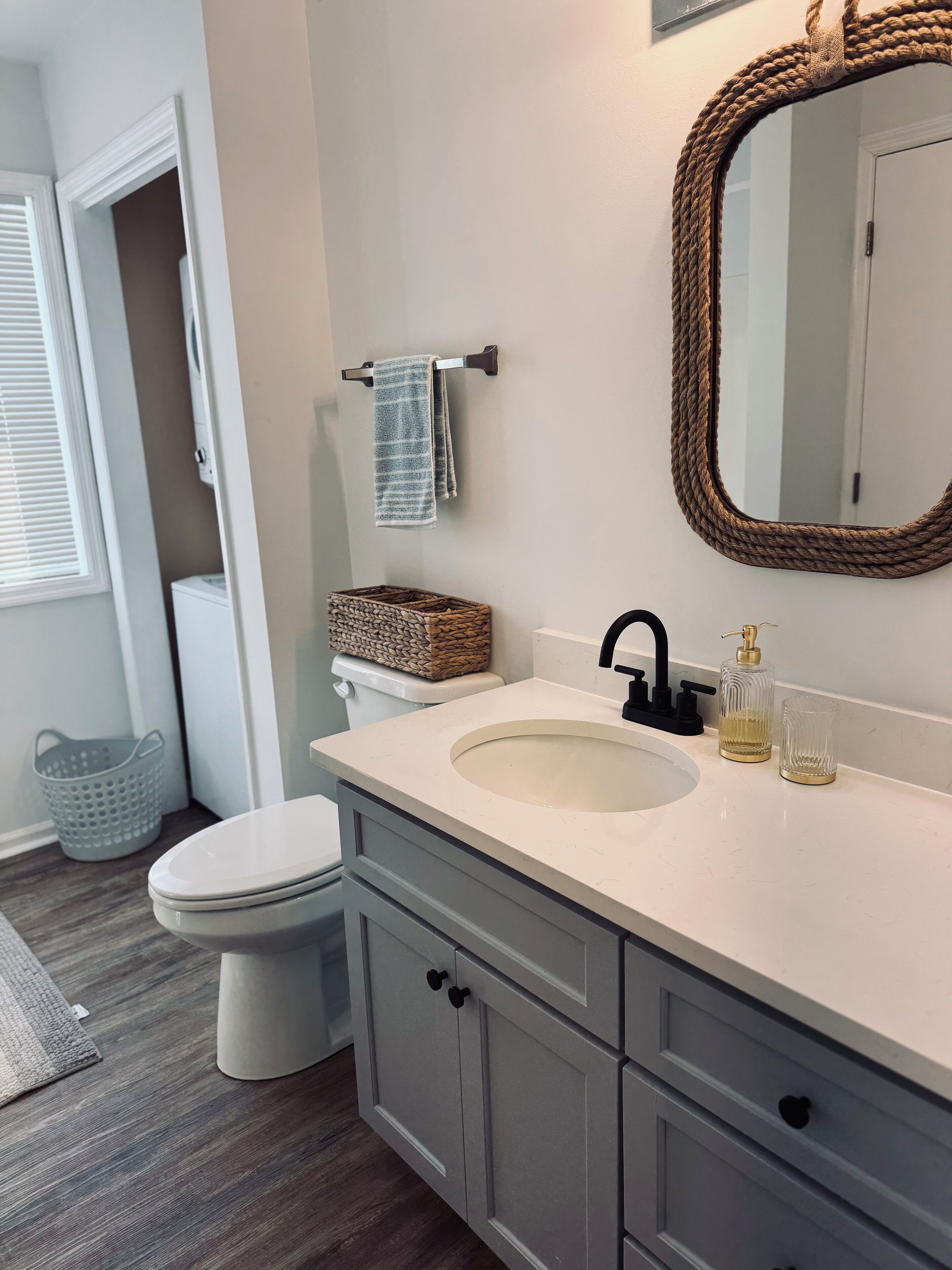 A bathroom with a white sink, a mirror, a toilet, and a basket on the wall.