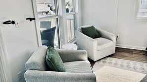 A modern living room with two grey armchairs, a green throw pillow, and a neon sign on the wall. - Modern, luxurious 1-bedroom condo in stunning Ocean Isle Beach (Ocean Isle Beach)