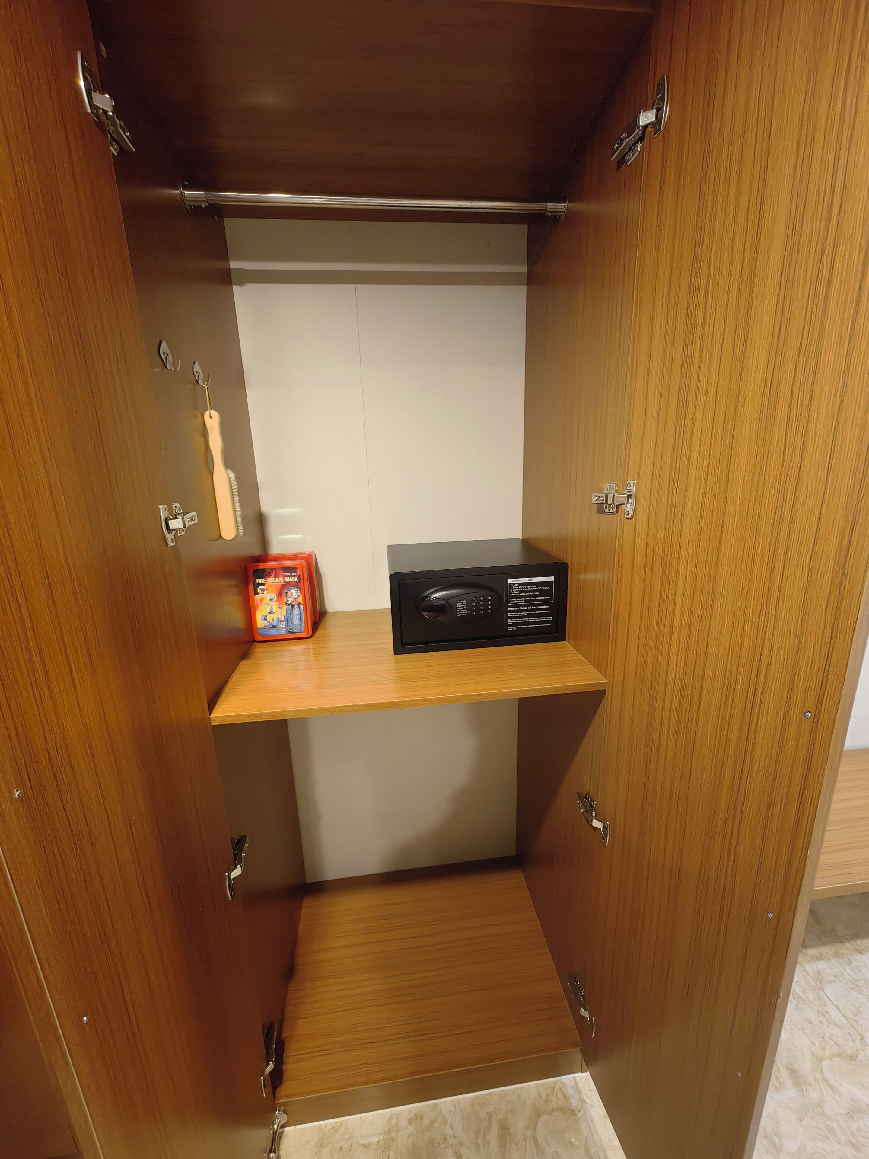 Un armario de madera con un estante, una cajita y un dispositivo electrónico negro.