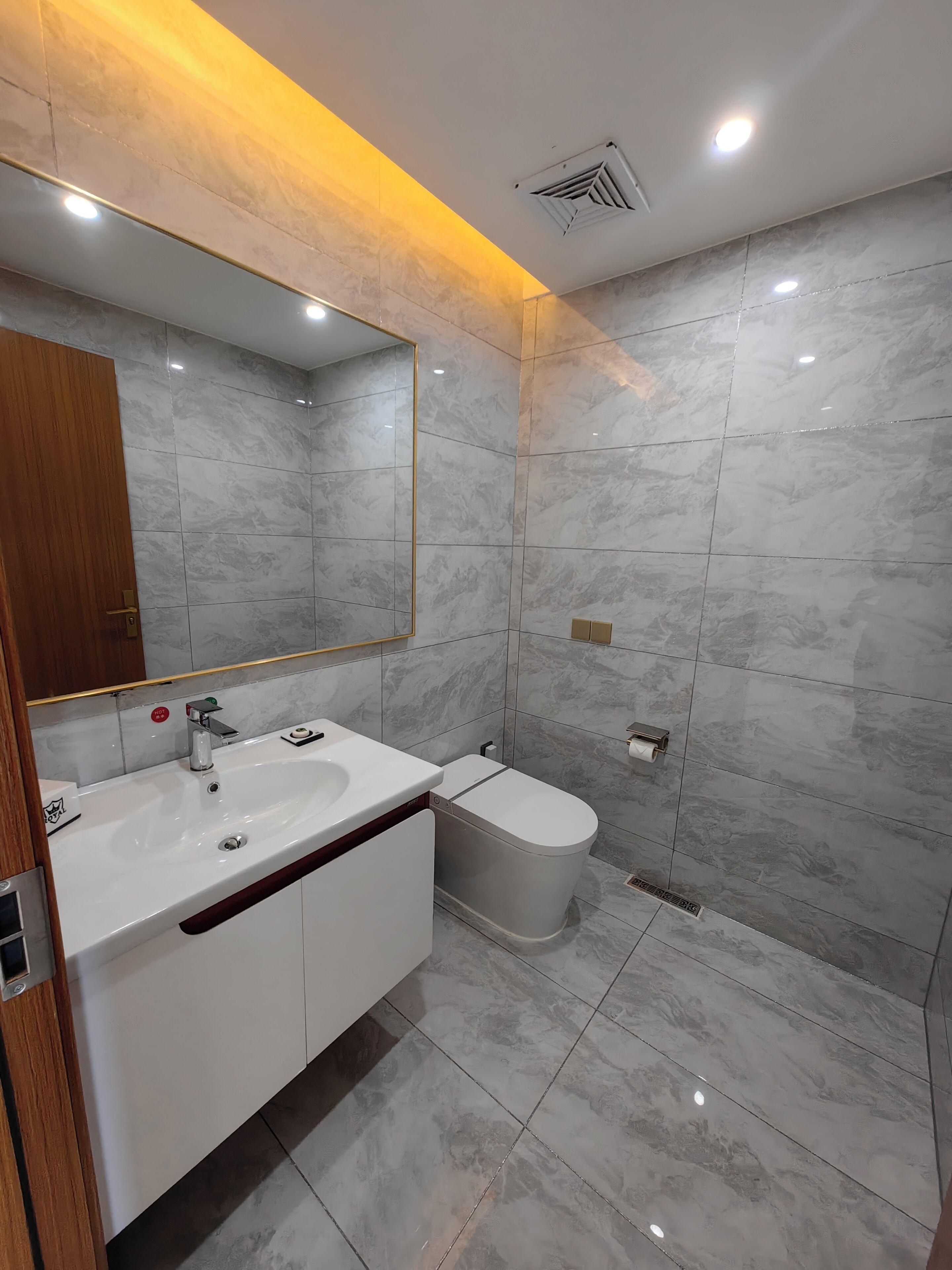 Un baño moderno con un espejo grande, dos lavamanos, un inodoro y una zona de ducha.