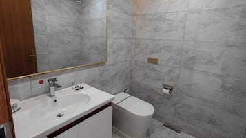 Un baño moderno con un espejo grande, dos lavamanos, un inodoro y una zona de ducha.