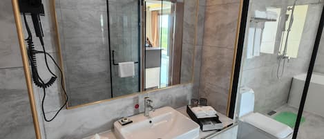 Un baño moderno con un espejo grande, un lavamanos y una ducha.