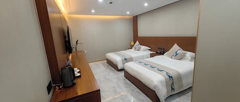 Une chambre d’hôtel avec deux lits, un bureau en bois, un téléviseur à écran plat et un sol en marbre.