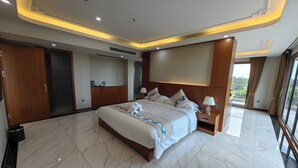 A modern hotel room with a large bed, a bedside table, a wardrobe, and a bathroom with a shower. - Royal International Hotel (Georgetown)