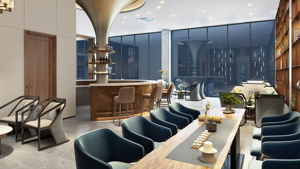 A modern dining area with a long wooden table, blue upholstered chairs, and a central bar area with shelves of bottles and glasses. - Royal International Hotel (Georgetown)