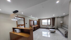 A modern hotel room with a wooden reception desk, a flat-screen TV, a sofa, and a dining area. - Royal International Hotel (Georgetown)