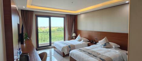 A modern hotel room with two beds, a desk, and a view of the outdoors.