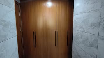 A room with a wooden wardrobe, white marble tiles, and a recessed ceiling light.