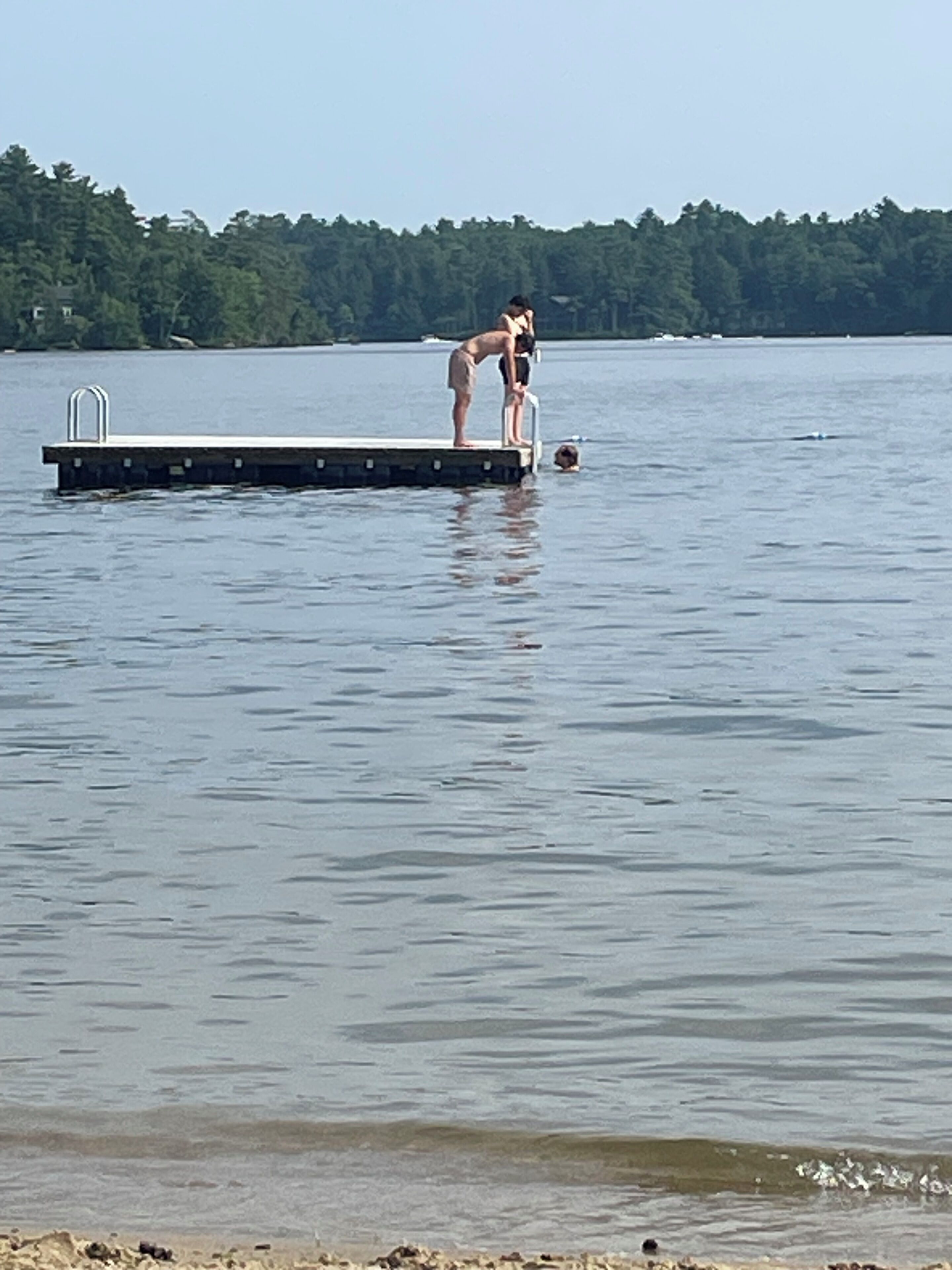 Ein Steg, der sich in ruhiges Wasser erstreckt, mit einer Person am Ende.