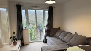 Ein modernes Wohnzimmer mit einem grauen Sofa, einem kleinen weißen Tisch und einem Glastisch.