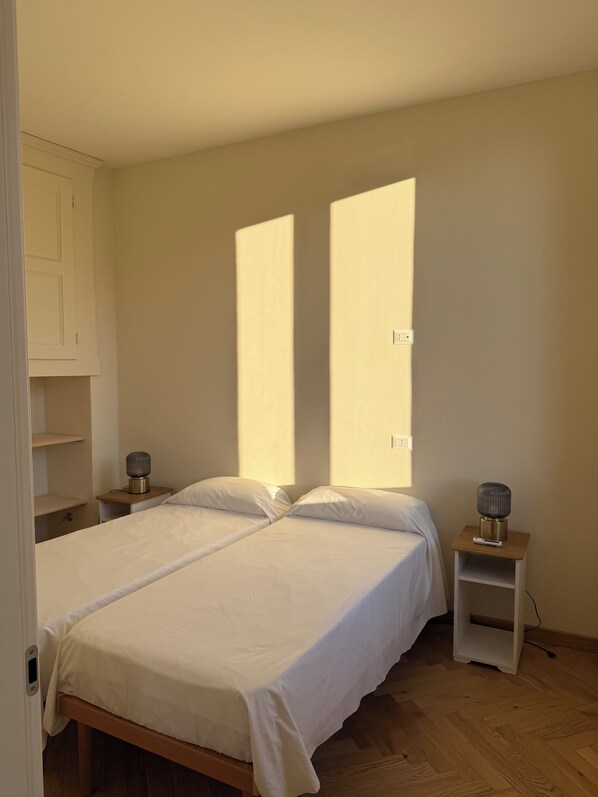 A bedroom with a double bed, two bedside tables with lamps, a wardrobe, and a window providing natural light. - Casa Rebei Menaggio (Menaggio)