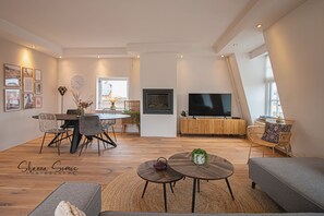 Een moderne woonkamer met een eethoek, een flatscreen-televisie en een groot raam.