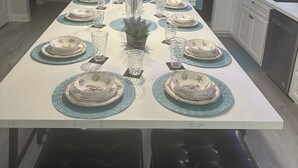 Une cuisine moderne avec des meubles blancs, des appareils en acier inoxydable et un îlot central aménagé pour les repas.