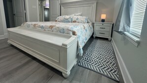 Une chambre à coucher avec un lit, des tables de chevet, une lampe et un tapis à motifs.